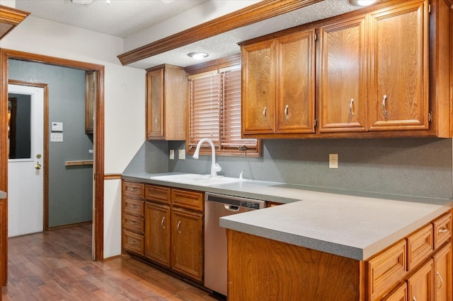 kitchen with hardwood / wood-style flooring, dishwasher, sink, and a textured ceiling