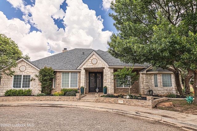 1510 Lancelot Ave, Wolfforth, TX 79382 - view of front of house featuring french doors, stone siding, a chimney, and a shingled roof