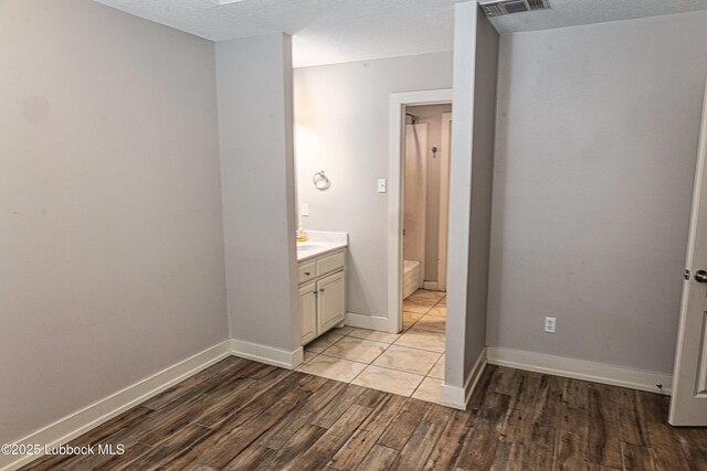 1510 Lancelot Ave, Wolfforth, TX 79382 - full bathroom featuring vanity, wood finished floors, a shower, a textured ceiling, and baseboards