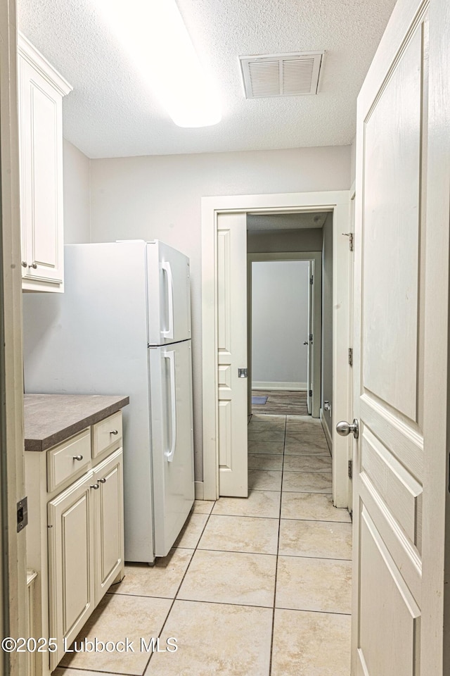 1510 Lancelot Ave, Wolfforth, TX 79382 - kitchen featuring a textured ceiling, light tile patterned floors, and freestanding refrigerator