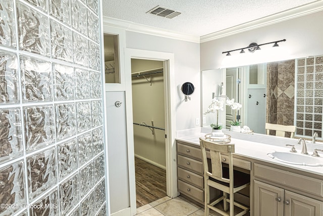 1510 Lancelot Ave, Wolfforth, TX 79382 - full bathroom featuring vanity, ornamental molding, a spacious closet, a textured ceiling, and tile patterned flooring
