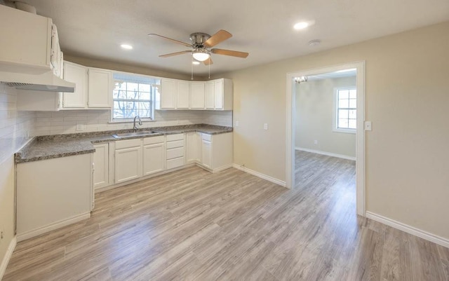 kitchen with white cabinetry, sink, decorative backsplash, a healthy amount of sunlight, and light wood-type flooring