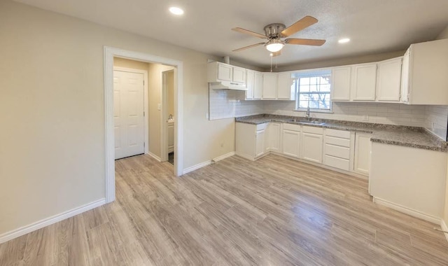 kitchen featuring white cabinetry, light hardwood / wood-style floors, sink, and decorative backsplash