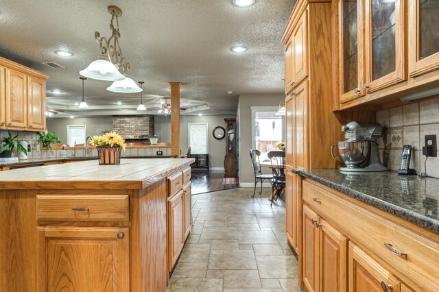 kitchen featuring tasteful backsplash, decorative light fixtures, a center island, a textured ceiling, and ceiling fan