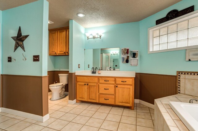 bathroom featuring toilet, wood walls, a textured ceiling, vanity, and tile patterned flooring