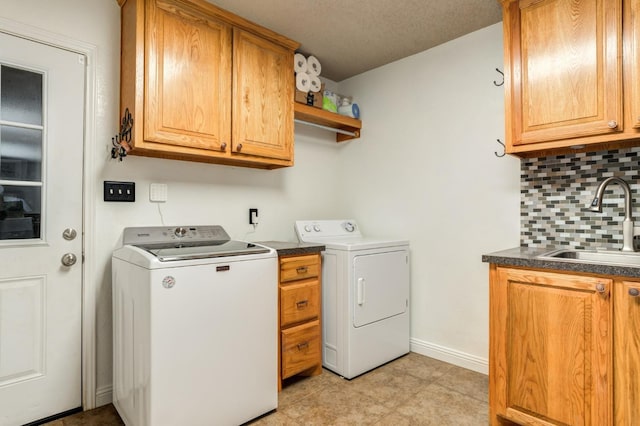 laundry area featuring washer and dryer, sink, a textured ceiling, and cabinets