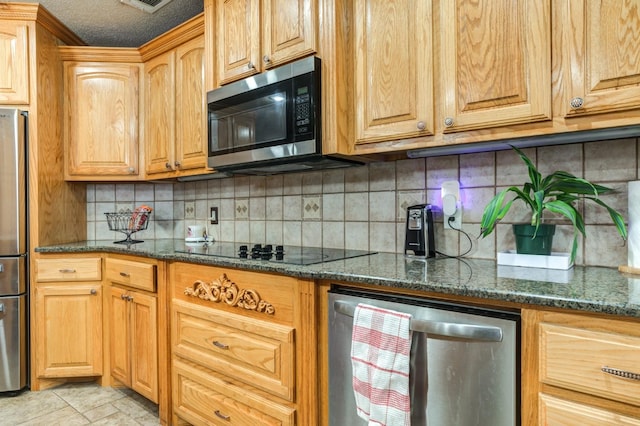 kitchen with stainless steel appliances, dark stone countertops, a textured ceiling, and decorative backsplash