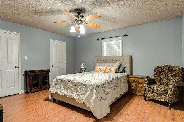 bedroom featuring ceiling fan, light hardwood / wood-style floors, and a textured ceiling