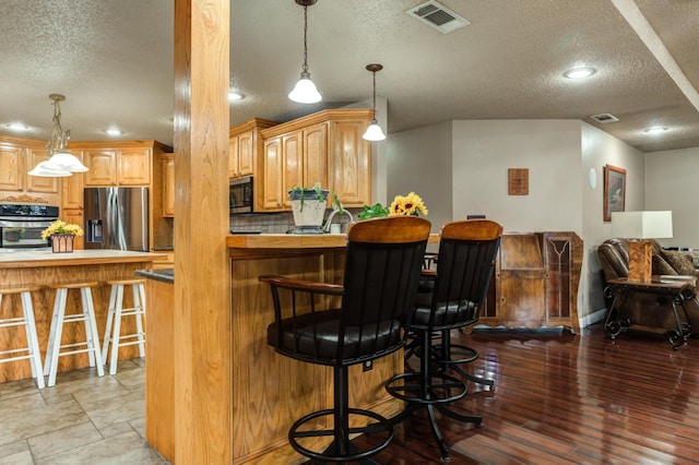 kitchen featuring a breakfast bar, a textured ceiling, and appliances with stainless steel finishes