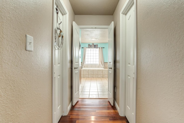 hallway with dark hardwood / wood-style flooring and a textured ceiling