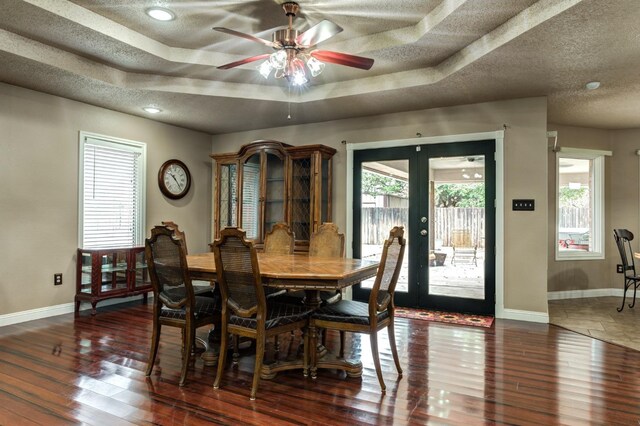 dining area with plenty of natural light, dark hardwood / wood-style flooring, a raised ceiling, and a textured ceiling