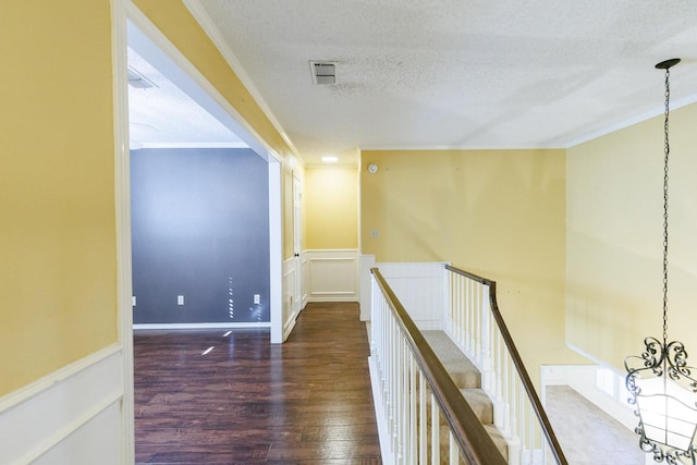 hall with a notable chandelier, crown molding, dark wood-type flooring, and a textured ceiling