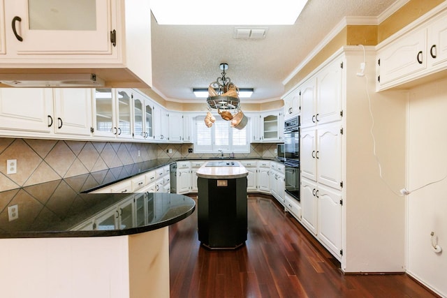 kitchen with dark wood-type flooring, double oven, tasteful backsplash, white cabinets, and kitchen peninsula