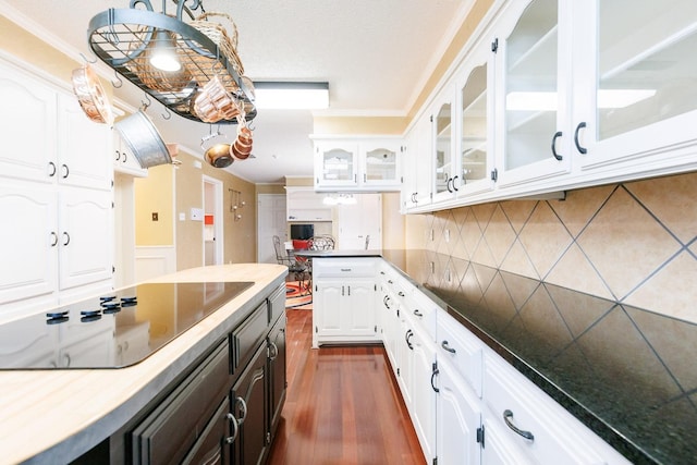 kitchen featuring white cabinetry, ornamental molding, black electric stovetop, and dark wood-type flooring