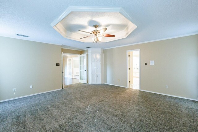 empty room with a tray ceiling, carpet, and a textured ceiling