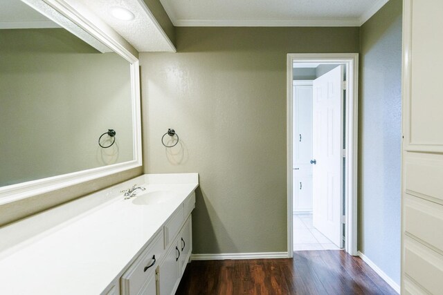 bathroom with hardwood / wood-style flooring, vanity, and crown molding