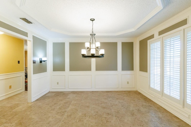 unfurnished dining area featuring a raised ceiling, ornamental molding, a textured ceiling, and a chandelier