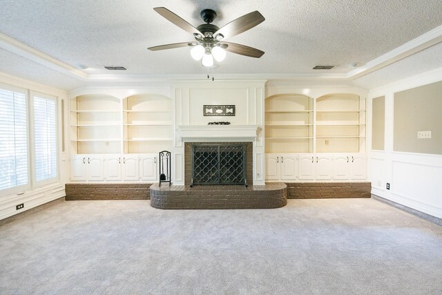 unfurnished living room featuring crown molding, a brick fireplace, carpet flooring, and a textured ceiling