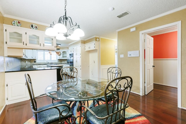 dining space featuring crown molding, dark wood-type flooring, and a chandelier