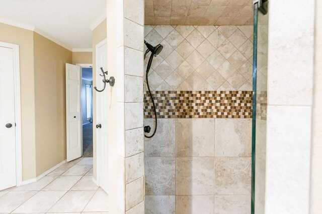 bathroom featuring tile patterned flooring, crown molding, and a tile shower