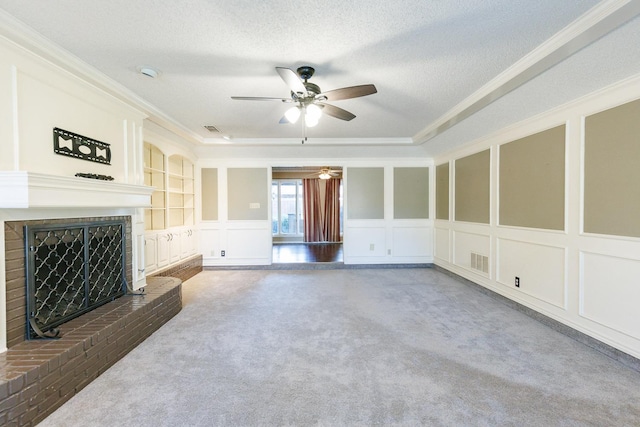 unfurnished living room featuring a brick fireplace, dark carpet, built in shelves, and a textured ceiling