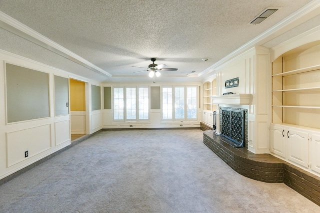 unfurnished living room with carpet floors, a fireplace, ornamental molding, a textured ceiling, and built in shelves