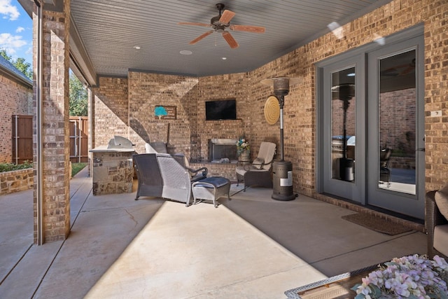 view of patio featuring exterior fireplace, ceiling fan, and exterior kitchen