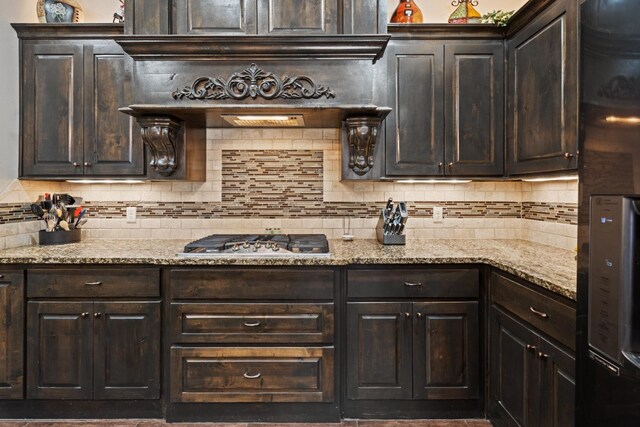 kitchen with backsplash, dark brown cabinets, and stainless steel gas stovetop