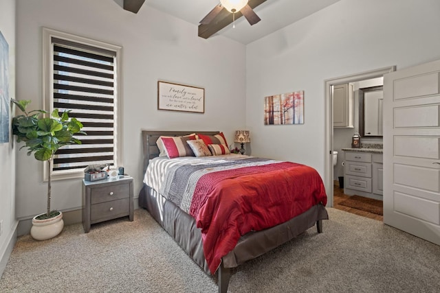 bedroom featuring ceiling fan, ensuite bath, light colored carpet, and beamed ceiling