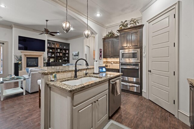 kitchen with appliances with stainless steel finishes, an island with sink, sink, dark hardwood / wood-style flooring, and dark brown cabinetry