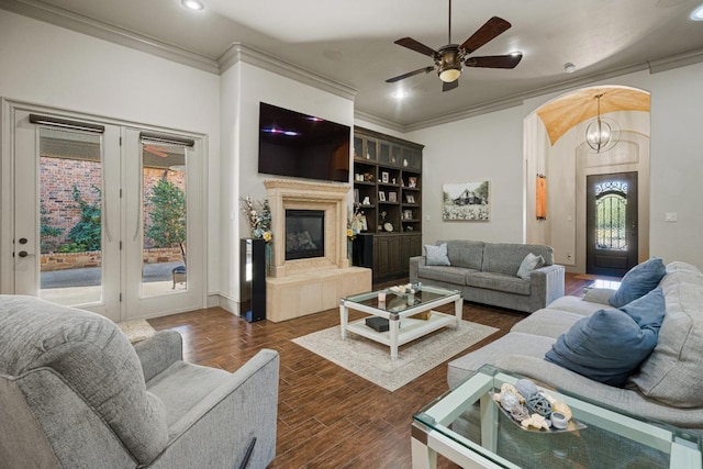 living room with crown molding, dark hardwood / wood-style floors, ceiling fan, and a fireplace