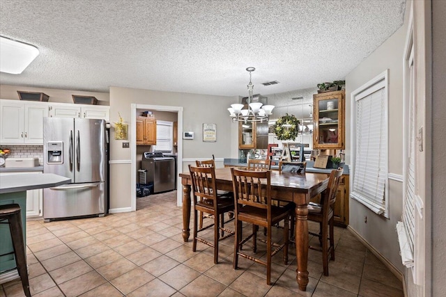 2917 Dove Ln, Denver City, TX 79323 - dining room with a chandelier, washer / dryer, light tile patterned floors, and a textured ceiling