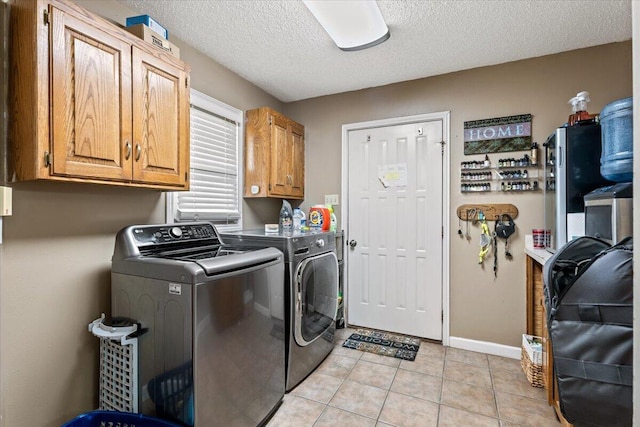 2917 Dove Ln, Denver City, TX 79323 - laundry room with separate washer and dryer, cabinet space, a textured ceiling, light tile patterned flooring, and baseboards