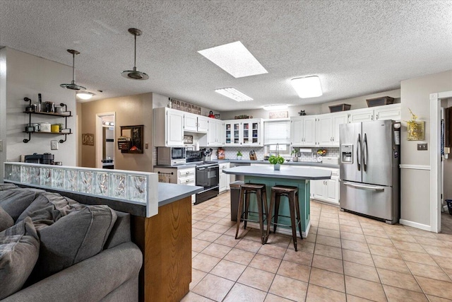 2917 Dove Ln, Denver City, TX 79323 - kitchen featuring stainless steel appliances, open floor plan, white cabinets, a kitchen breakfast bar, and a kitchen island