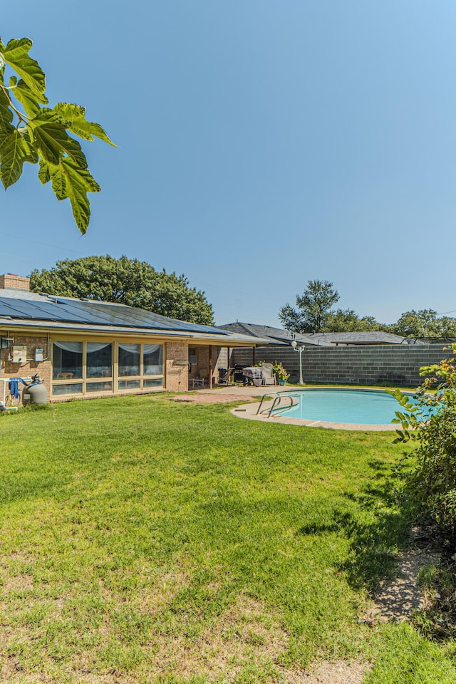 view of swimming pool featuring a yard, a sunroom, and a fenced in pool