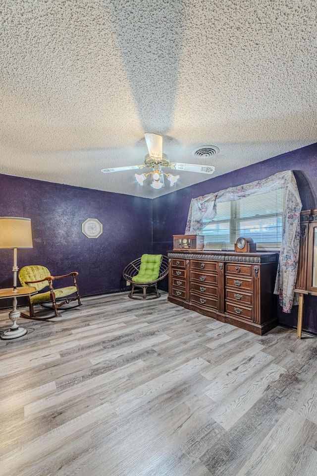 bedroom with a textured ceiling, wood finished floors, ceiling fan, and visible vents