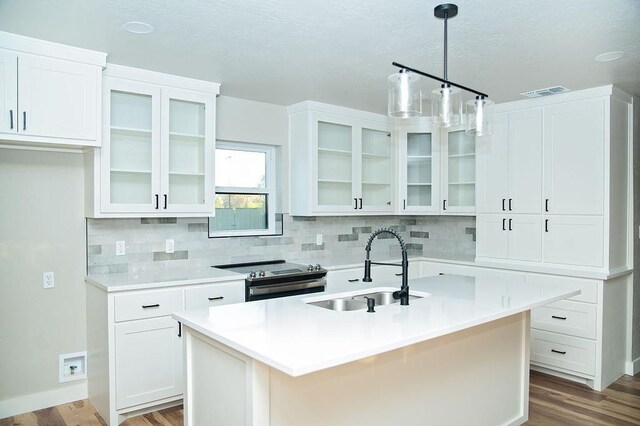 kitchen featuring sink, white cabinets, hanging light fixtures, a kitchen island with sink, and stainless steel electric range