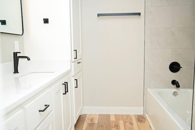 bathroom featuring hardwood / wood-style flooring, vanity, and tiled shower / bath combo