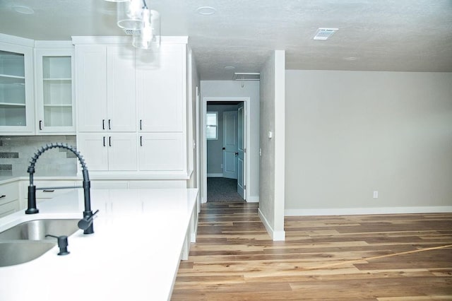 kitchen featuring tasteful backsplash, sink, white cabinets, and light wood-type flooring