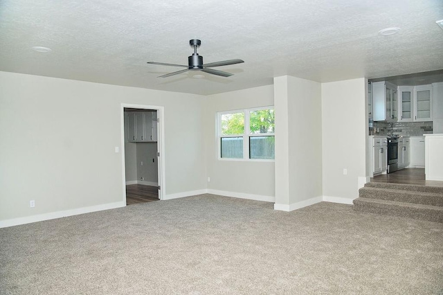 unfurnished living room featuring carpet floors, a textured ceiling, and ceiling fan