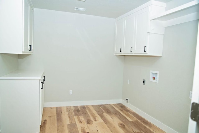 laundry area featuring cabinets, light hardwood / wood-style flooring, hookup for an electric dryer, washer hookup, and a barn door