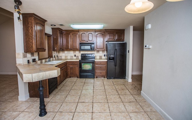 kitchen with light tile patterned flooring, sink, backsplash, black appliances, and dark brown cabinets