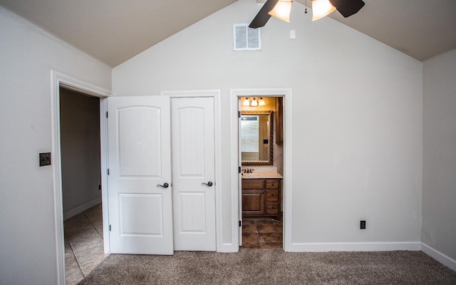 unfurnished bedroom with ensuite bath, vaulted ceiling, carpet floors, a closet, and ceiling fan