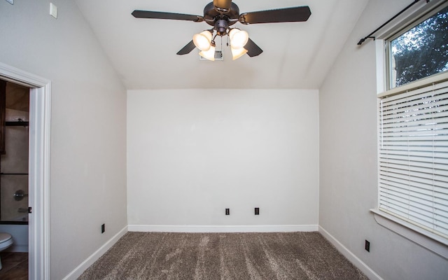 interior space with lofted ceiling, dark carpet, and ceiling fan