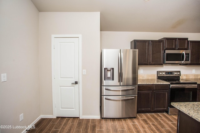 7314 29th St, Lubbock, TX 79407 - kitchen featuring appliances with stainless steel finishes, wood tiled floors, dark brown cabinets, and light stone counters