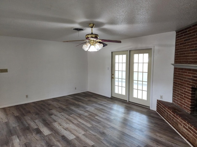 unfurnished living room featuring ceiling fan, dark hardwood / wood-style floors, a fireplace, and a textured ceiling