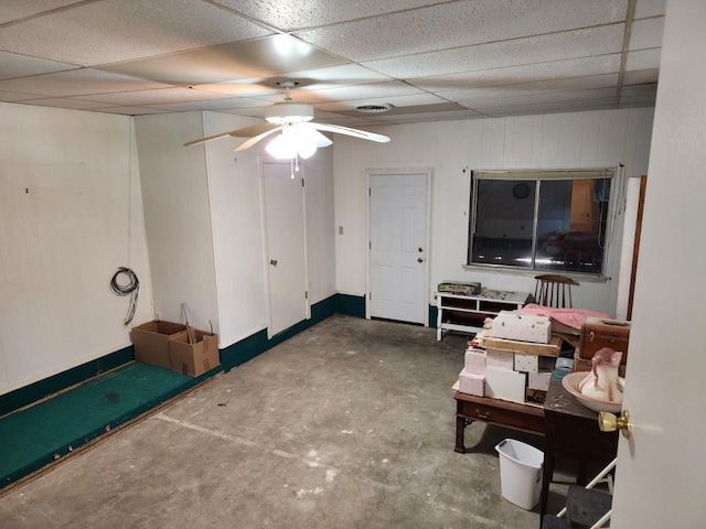 interior space with a paneled ceiling, concrete flooring, and ceiling fan