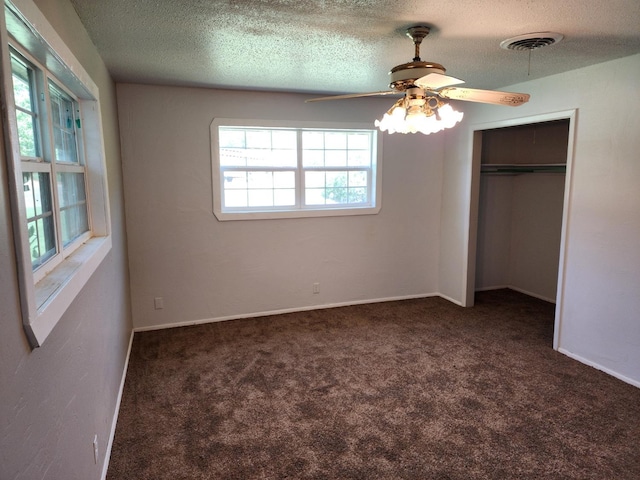 unfurnished bedroom featuring dark colored carpet, ceiling fan, a textured ceiling, and a closet