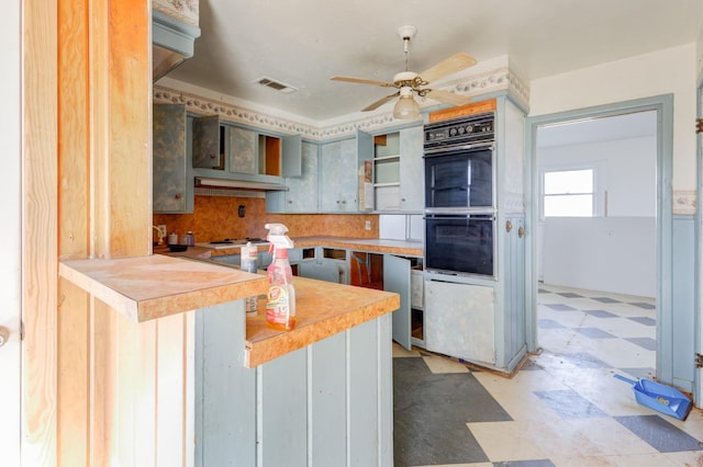 kitchen featuring ceiling fan, black double oven, white stovetop, and kitchen peninsula