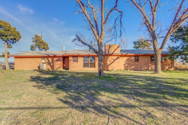 back of property with central AC unit and a lawn